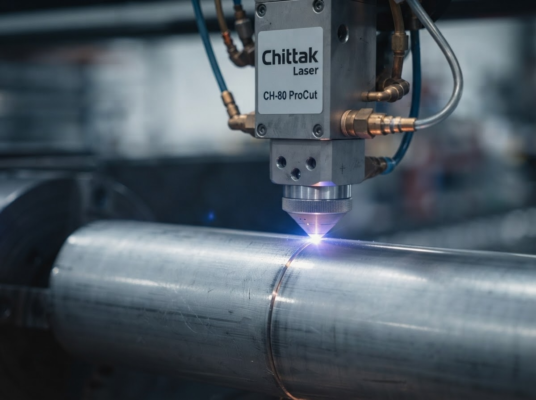 Macro close-up of a Chittak laser cutting head precision-cutting an 80mm stainless steel round tube, with brilliant blue laser contact and tiny sparks.